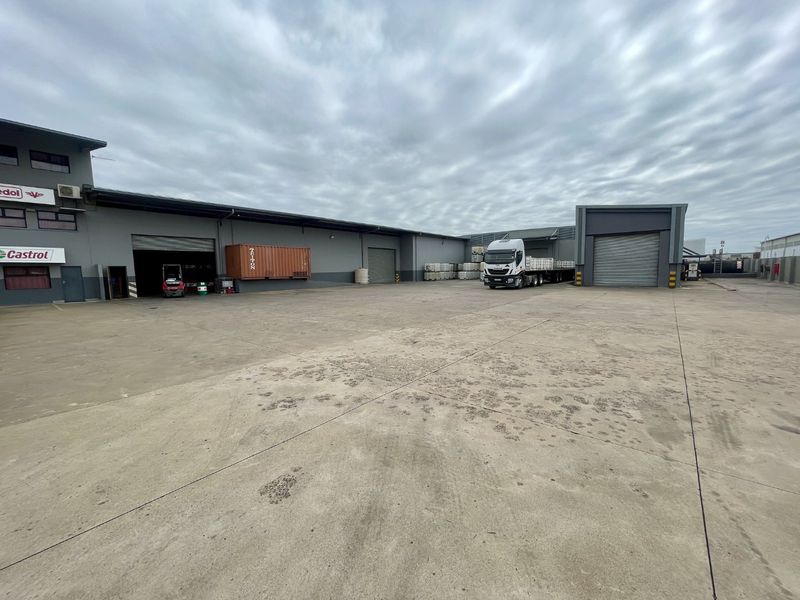Spacious industrial concrete yard featuring multiple roller shutter doors, providing efficient access for loading and logistics operations.