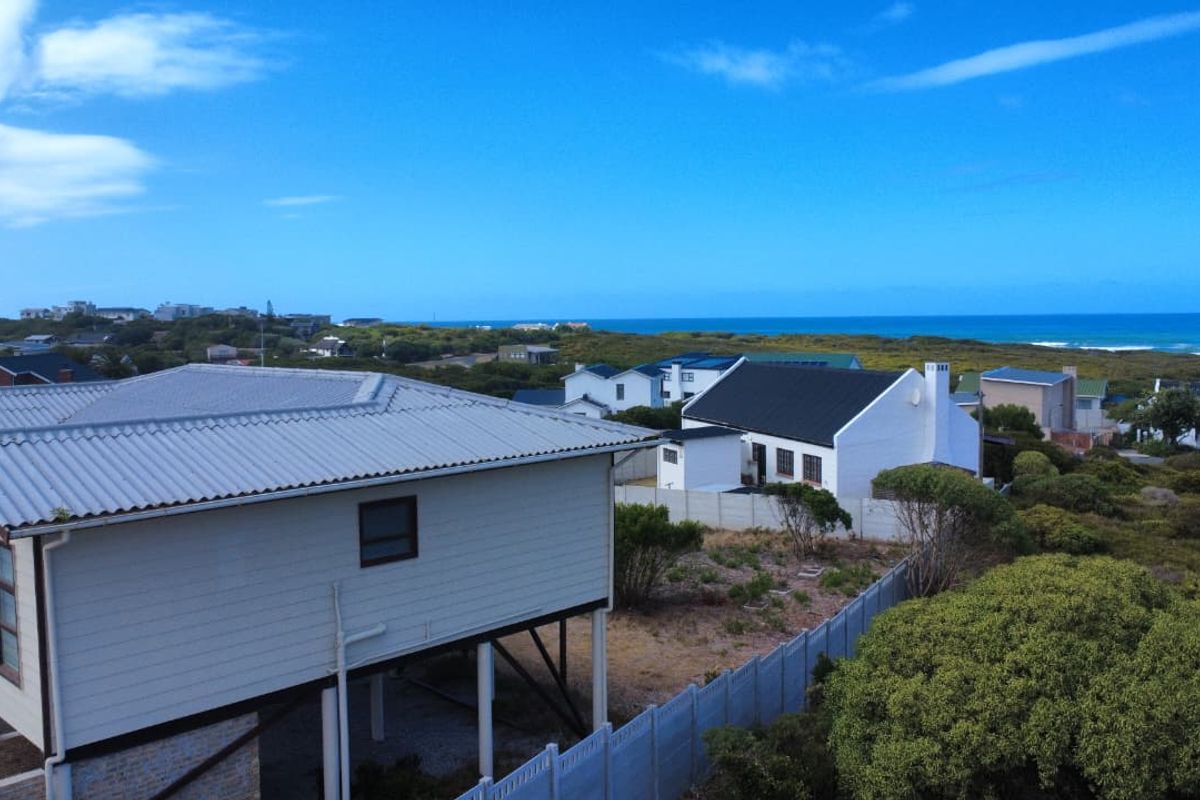 An elevated aerial view of a coastal residential area, showcasing the surrounding landscape, nearby homes, and proximity to the ocean.