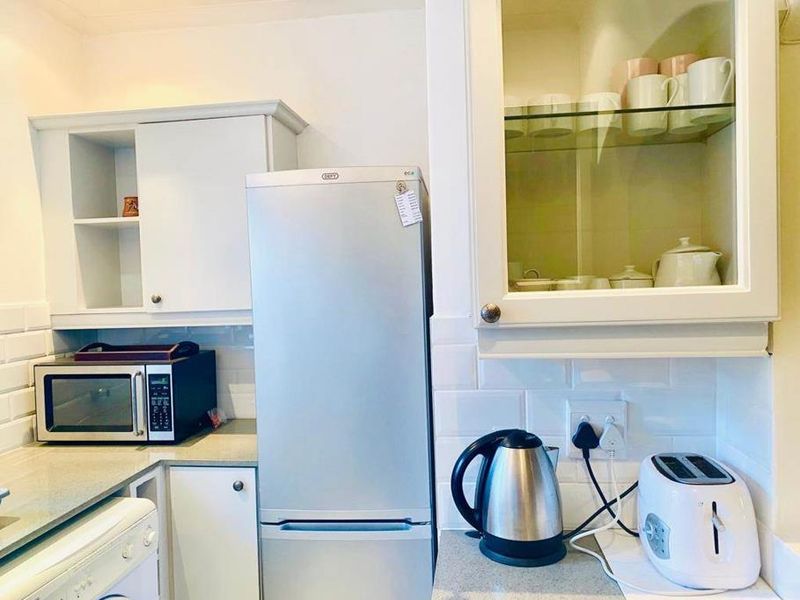 A compact kitchen area featuring white cabinetry, subway tile backsplash, and stone-look countertops, providing a clean and functional workspace.