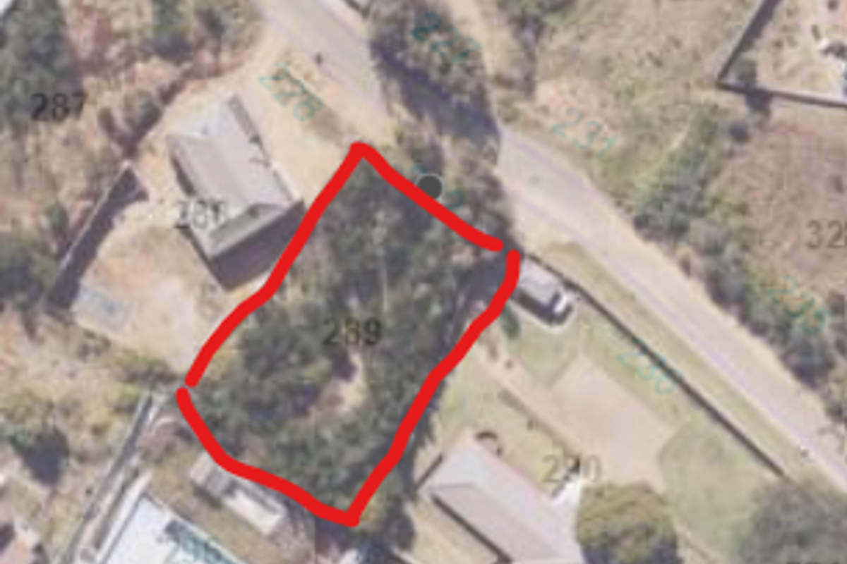 An aerial view of a vacant residential plot, highlighted in red, showing its location and boundaries within the surrounding neighborhood.
