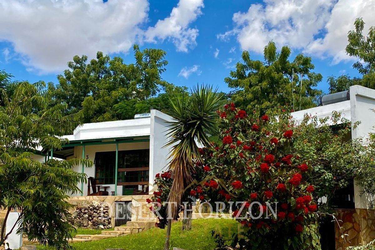 A view of the lodge exterior featuring a covered patio, stone-clad foundation, and solar water heating system on the roof.