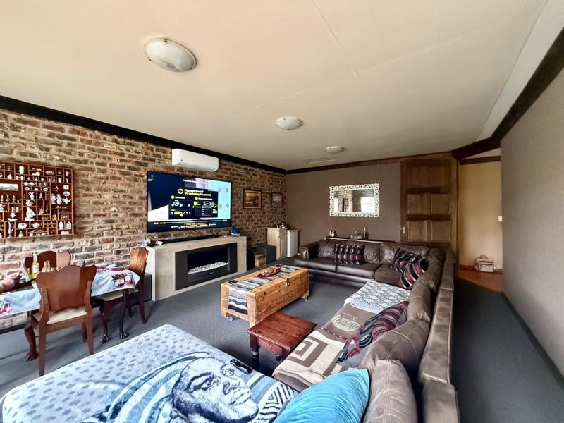 Spacious living room featuring an exposed brick feature wall, built-in electric fireplace, and split-system air conditioning unit.