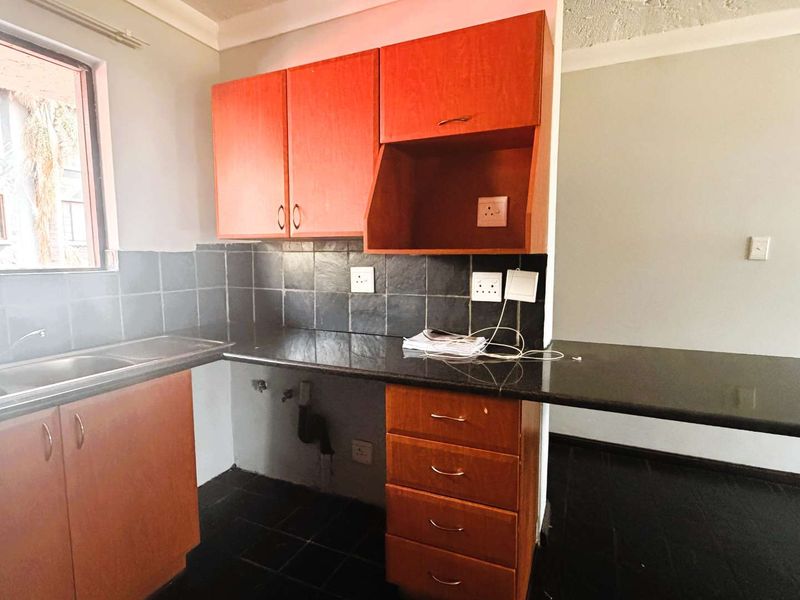 A functional kitchen featuring laminate cabinetry, granite countertops, a stainless steel sink, and tiled backsplash, offering a clean and practical workspace.
