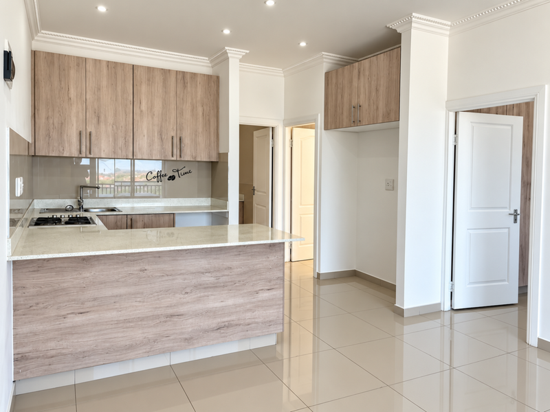 Modern kitchen featuring light wood-grain cabinetry, stone countertops, gas hob, and sleek tiled flooring in an open-plan layout.