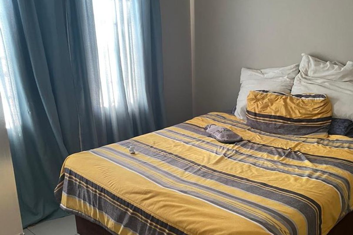 A functional bedroom featuring tiled flooring and neutral wall finishes, providing a comfortable and well-lit sleeping space.