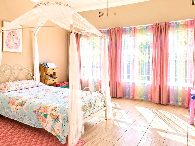 A bright and well-maintained bedroom featuring tiled flooring and large windows with natural light.