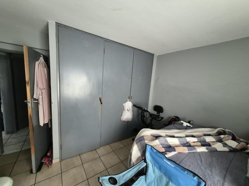A bedroom featuring built-in cupboards and tiled flooring, requiring cosmetic updates to the cabinetry and door frames to improve overall presentation.