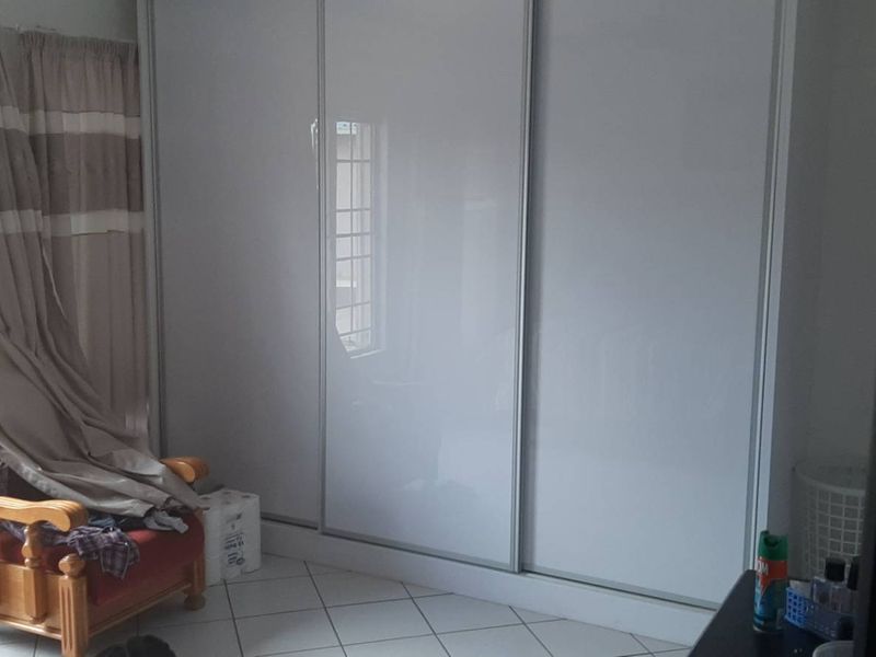 A bedroom featuring tiled flooring and a large, modern built-in sliding door wardrobe.
