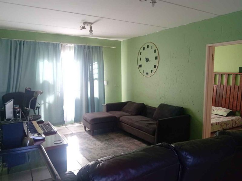 A living room area featuring tiled flooring and a sliding door leading to an outdoor space, with green painted walls.
