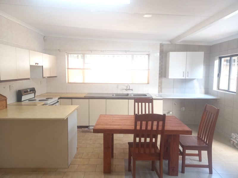 A functional kitchen featuring tiled flooring, built-in cabinetry, a double basin sink, and an electric stove, offering a practical layout for daily meal preparation.