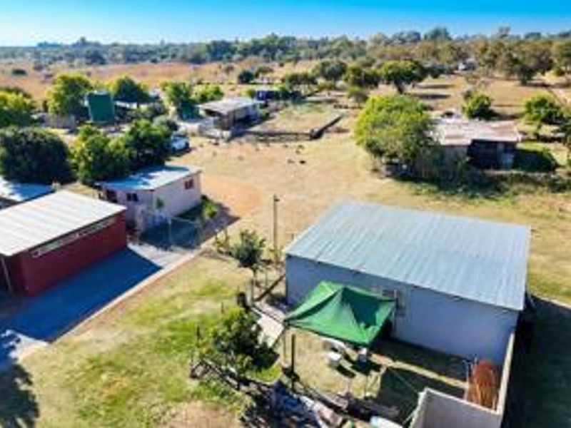 Aerial view of the small holding property showcasing multiple outbuildings, corrugated metal roofing, and expansive surrounding land.