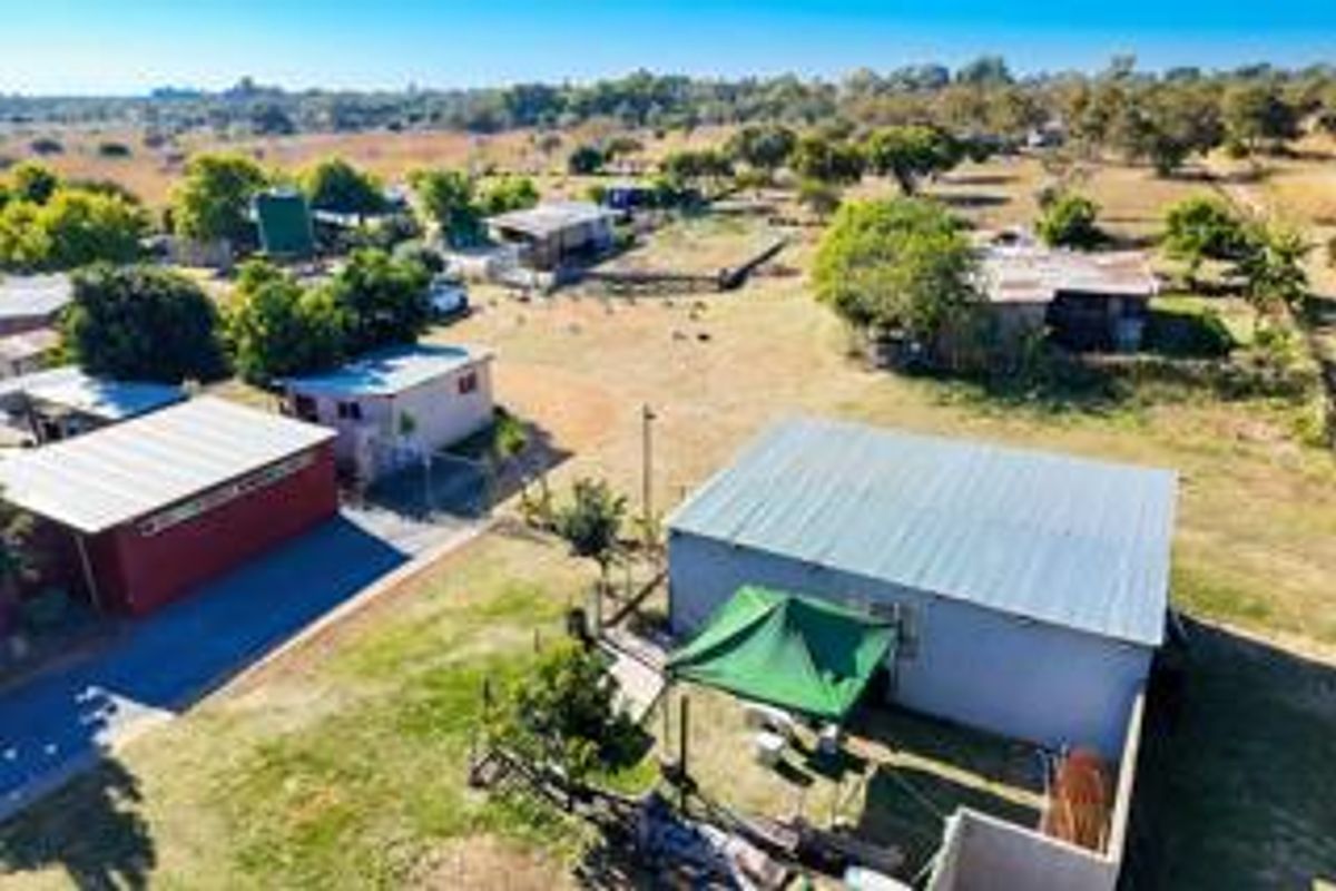 Aerial view of the small holding property showcasing multiple outbuildings, corrugated metal roofing, and expansive surrounding land.