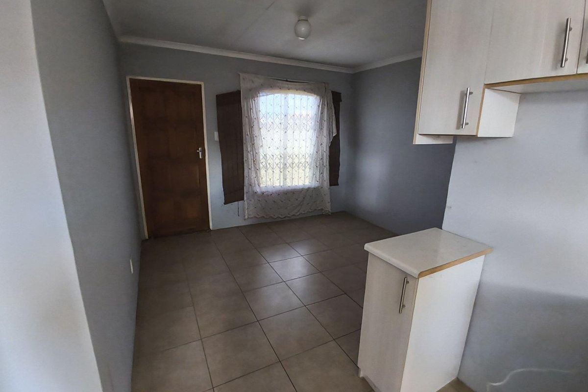 A functional, empty room featuring tiled flooring, neutral wall tones, and built-in cabinetry, offering a versatile space for living or dining arrangements.