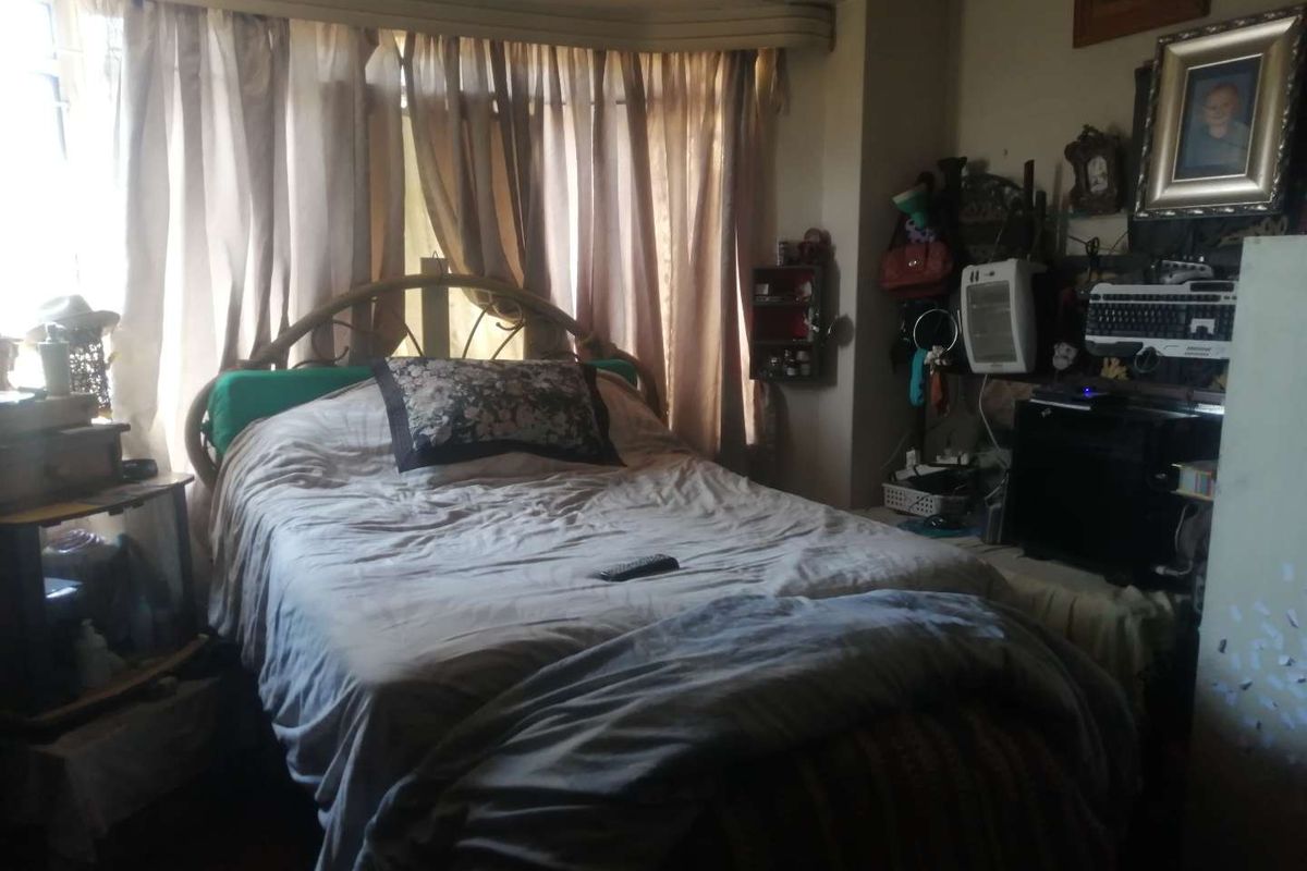 A bedroom featuring a large bay window with integrated curtain track and wooden flooring.