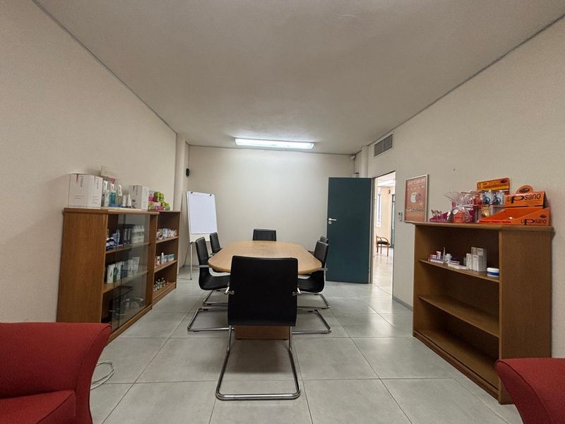 A functional office space featuring tiled flooring, fluorescent lighting, and an integrated air conditioning vent, suitable for a professional meeting or workspace environment.