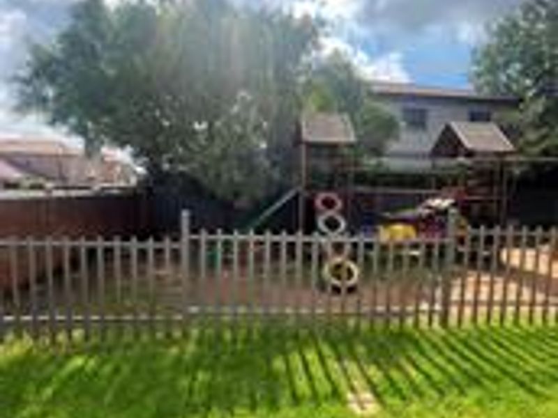 A private garden area featuring a well-maintained lawn, enclosed by a wooden picket fence and boundary wall.