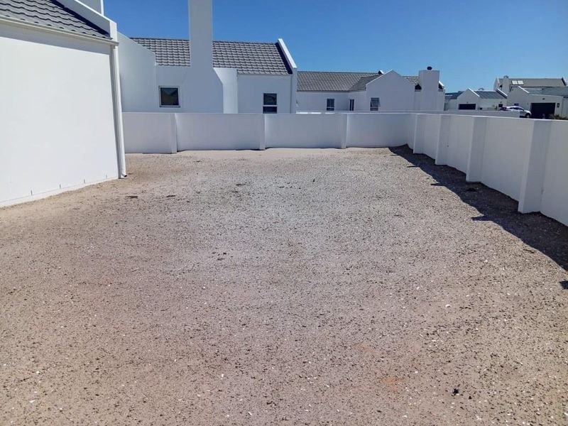 A spacious, unlandscaped rear yard area enclosed by white boundary walls, offering a blank canvas for future garden design or outdoor living space.