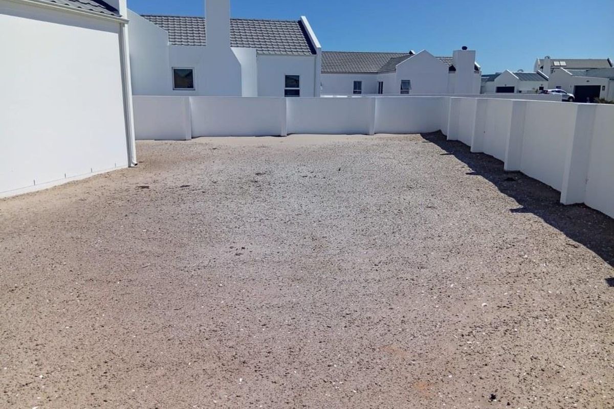 A spacious, unlandscaped rear yard area enclosed by white boundary walls, offering a blank canvas for future garden design or outdoor living space.