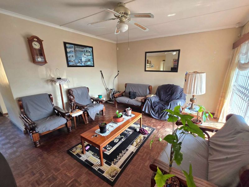 A living room featuring classic parquet flooring and a ceiling fan, offering a functional space with potential for modern updates.