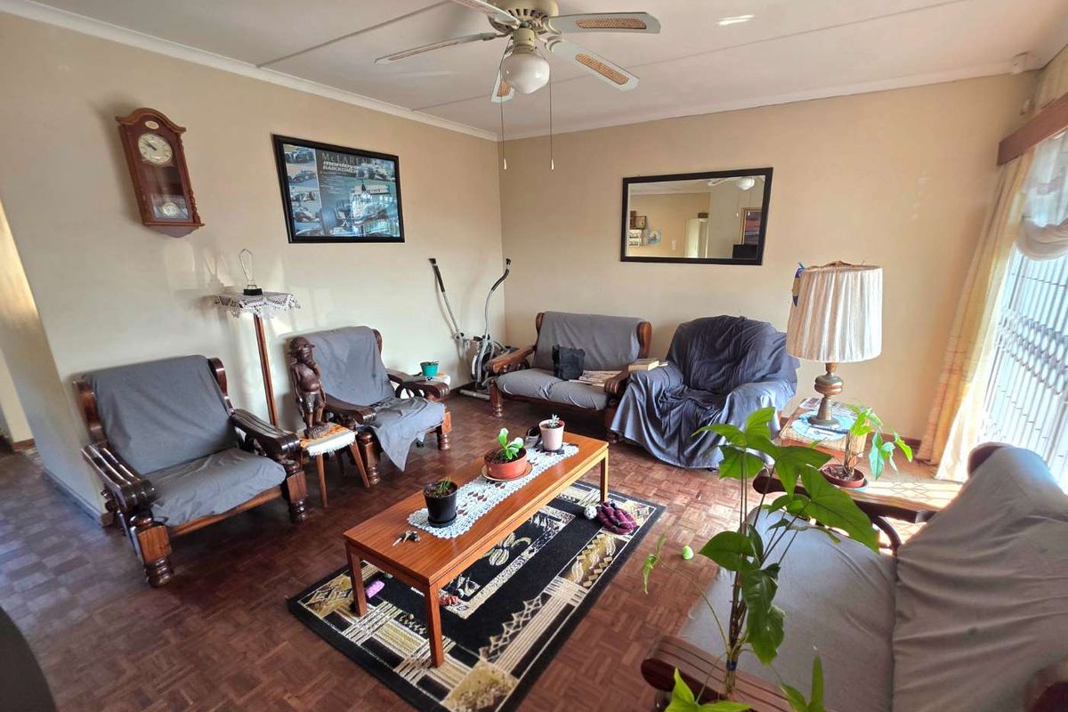 A living room featuring classic parquet flooring and a ceiling fan, offering a functional space with potential for modern updates.