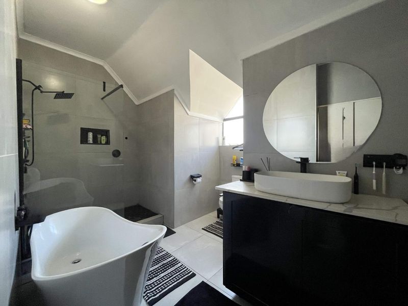 Modern bathroom featuring a sleek freestanding bathtub, a spacious walk-in shower with a glass screen, and a contemporary vanity with a vessel sink.