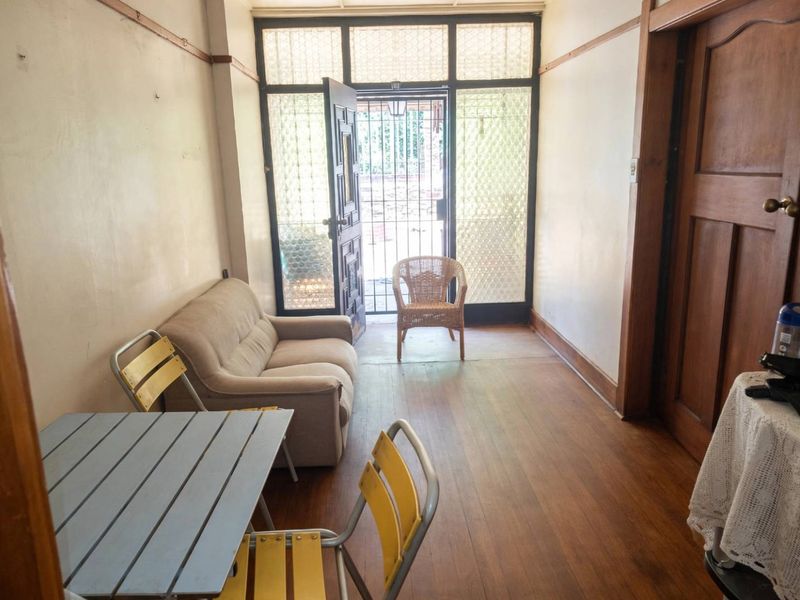 An entry area featuring original timber flooring, picture rails, and a secure glass-paneled entrance door with a security gate.