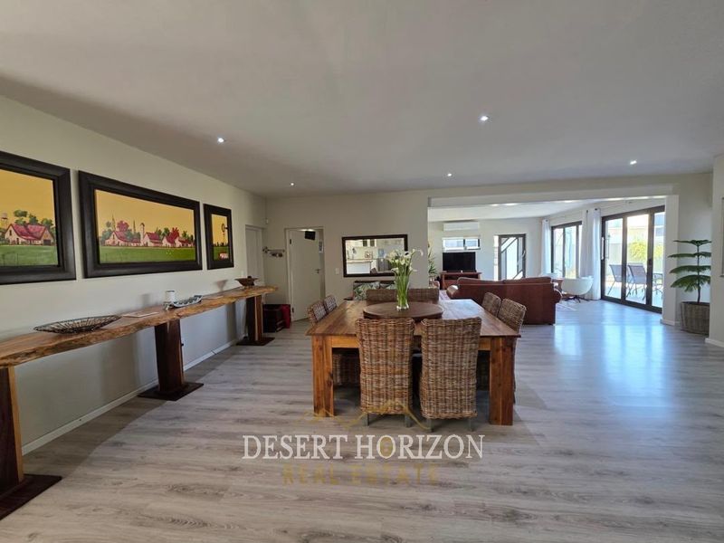 Spacious open-plan living and dining area featuring modern laminate flooring, recessed lighting, and large sliding glass doors leading to an outdoor patio.