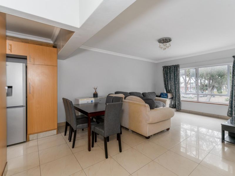Open-plan living and dining area featuring tiled flooring, built-in cabinetry, and large windows providing natural light.