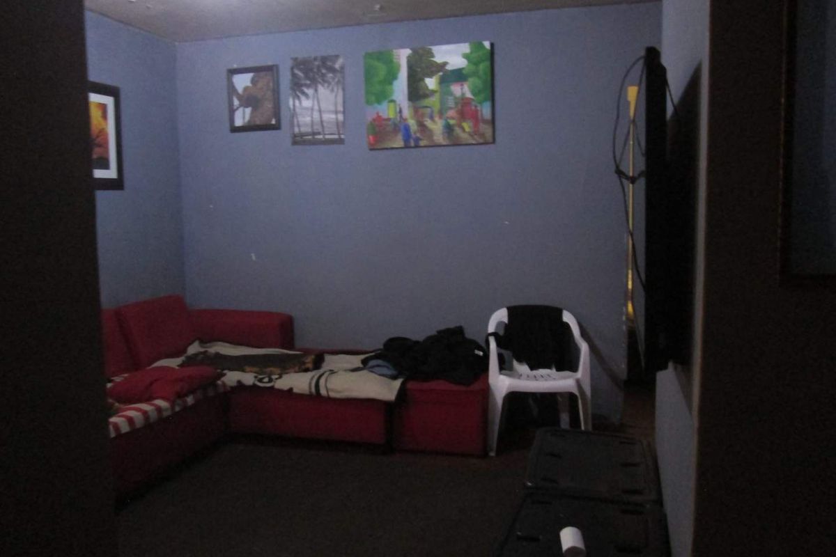 A dimly lit living room space with dark wall paint, requiring improved lighting and updated finishes to enhance the overall atmosphere.
