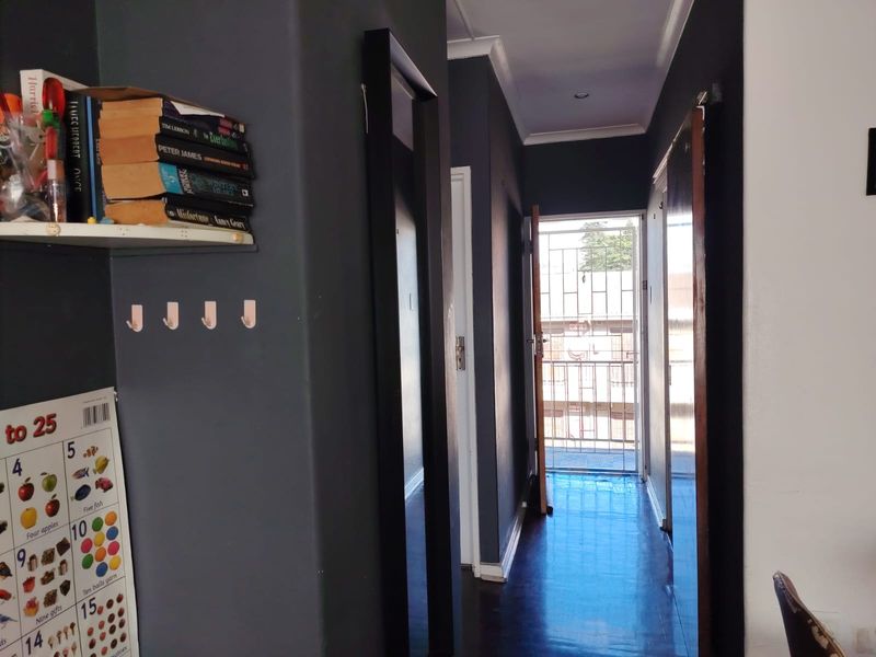 A functional hallway featuring dark painted walls, timber flooring, and a secure metal gate leading to the exterior.