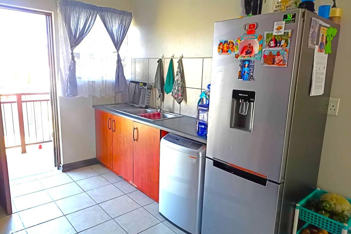 A functional kitchen featuring laminate cabinetry, a stainless steel sink, tiled backsplash, and direct access to an outdoor balcony area.
