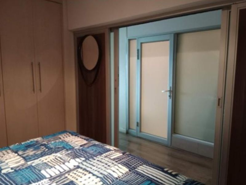 A bedroom featuring built-in cupboards, laminate flooring, and a sliding glass door leading to an adjacent space.