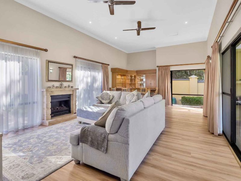 Spacious living room featuring a fireplace, built-in bar, vaulted ceilings with fans, and large sliding glass doors providing access to the outdoor area.