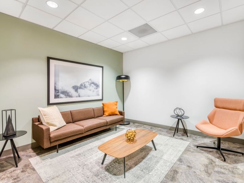A modern office lounge area featuring a suspended ceiling with recessed lighting and durable vinyl flooring.