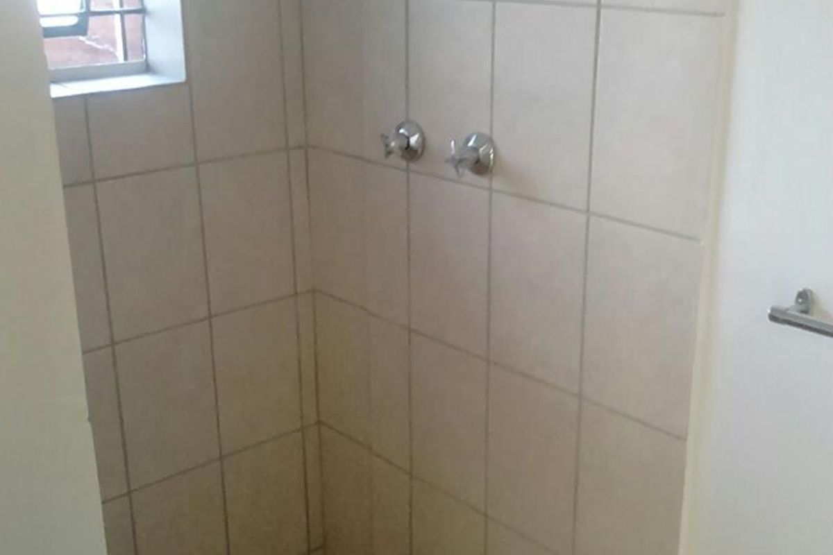A shower enclosure featuring tiled walls and floor, currently requiring maintenance and the installation of shower fittings.
