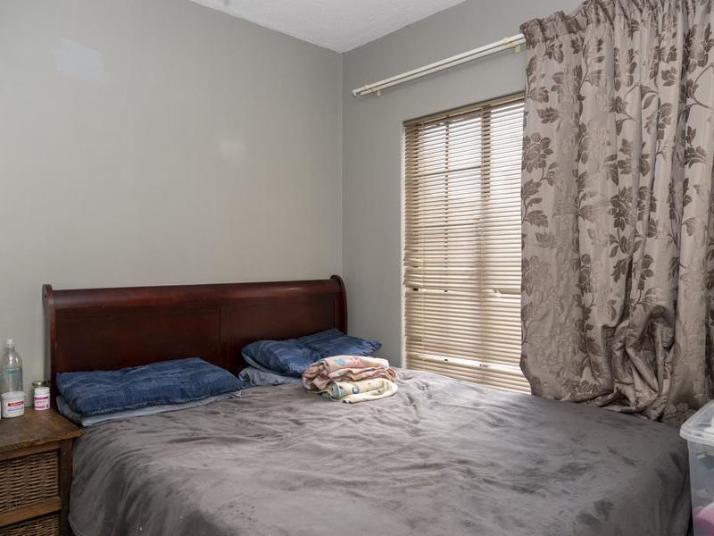 A bedroom featuring a window with fitted blinds and curtain tracks, finished with neutral wall paint.
