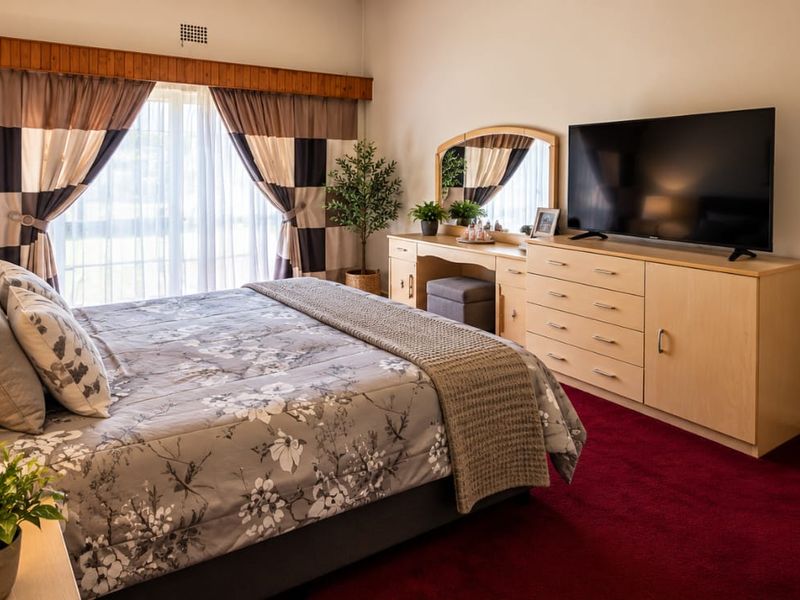 A well-maintained bedroom featuring carpeted flooring, a built-in wardrobe, and sliding glass doors that provide natural light.