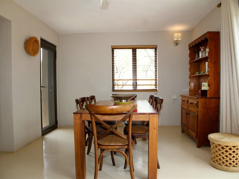 A dining room featuring neutral walls, tiled flooring, a window with blinds, and a glass panel door leading to an outdoor area.