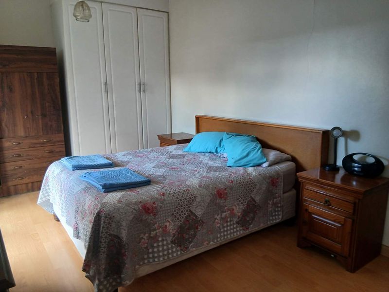 A bedroom featuring built-in white wardrobes and laminate flooring.