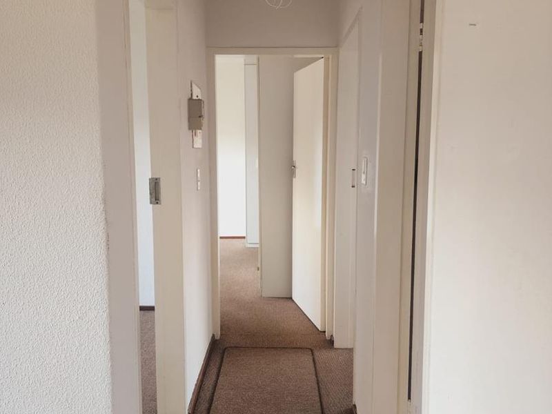 A functional interior hallway featuring carpeted flooring and access to the ceiling, connecting multiple rooms within the property.