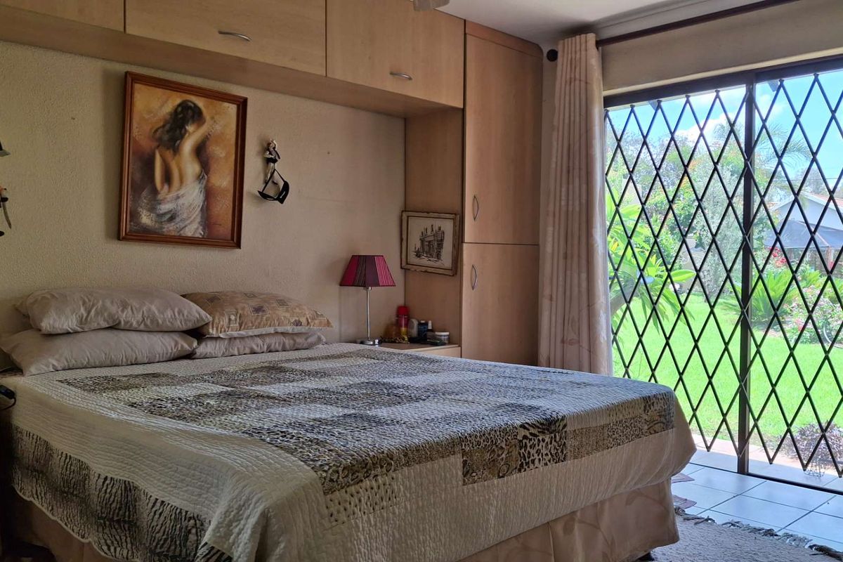 A bedroom featuring built-in wooden cabinetry and a sliding glass door with security gate, providing direct access to the garden.