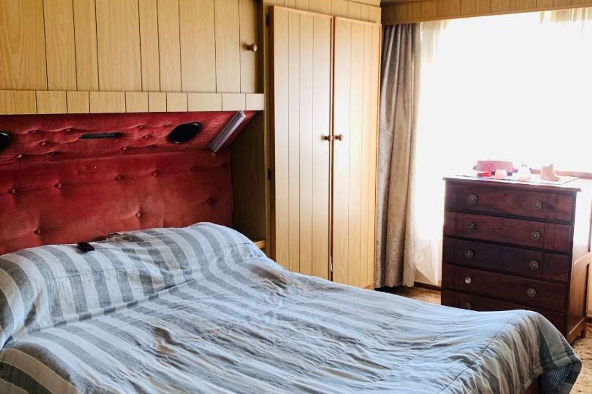 A bedroom featuring extensive built-in wooden cabinetry and a ceiling fan, offering significant storage space with a dated aesthetic.