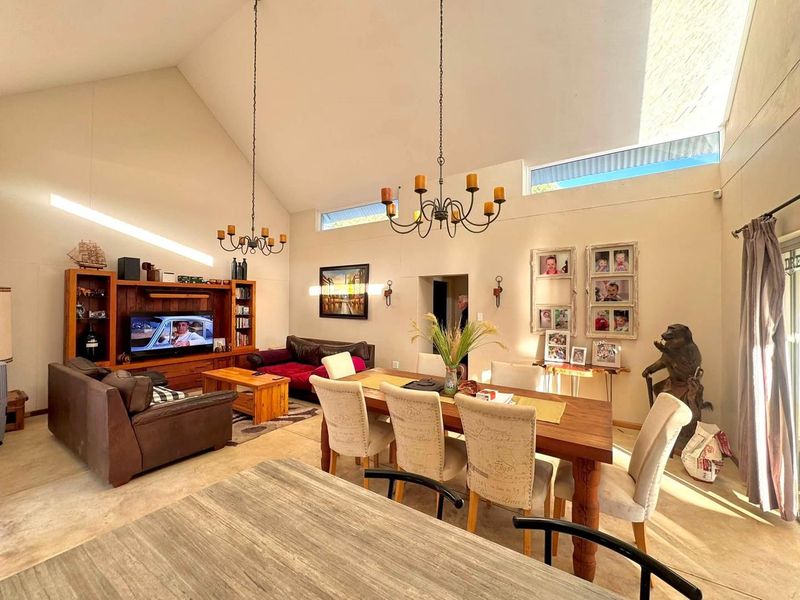 Spacious open-plan living and dining area featuring high vaulted ceilings, clerestory windows for natural light, and polished concrete flooring.
