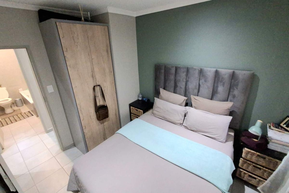 A well-maintained bedroom featuring a built-in wardrobe, neutral tiled flooring, and an en-suite bathroom access.