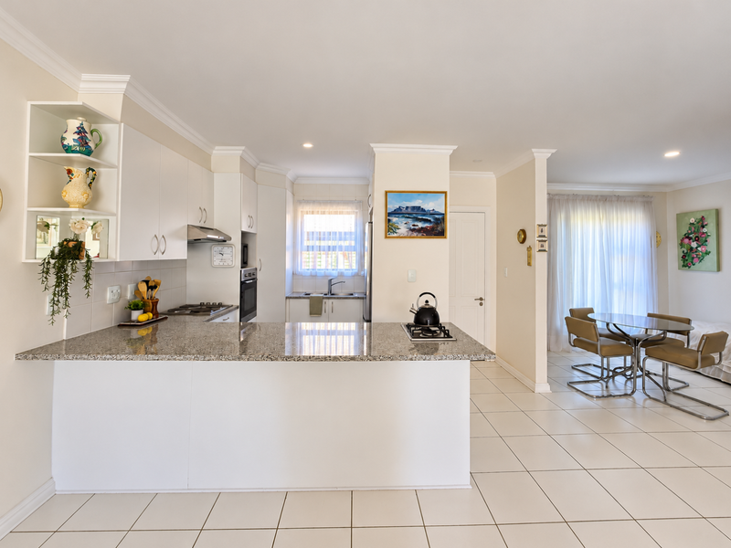 Open-plan kitchen and dining area featuring granite countertops, built-in appliances, tiled flooring, and neutral finishes, creating a bright and functional living space.