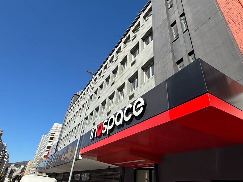 A low-angle exterior view of the office building facade featuring prominent commercial signage and a modern entrance canopy.