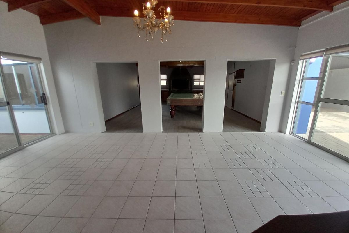 Spacious living area featuring exposed timber beam ceilings, large sliding glass doors, and tiled flooring, providing an open layout with multiple access points.