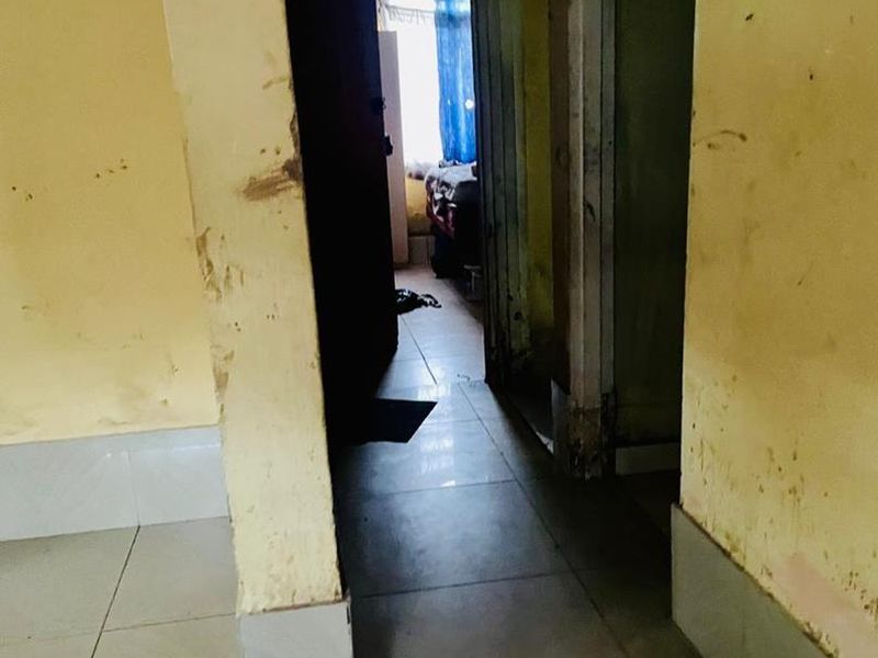 A narrow interior hallway featuring tiled flooring and walls showing significant signs of wear and surface damage requiring maintenance and repainting.