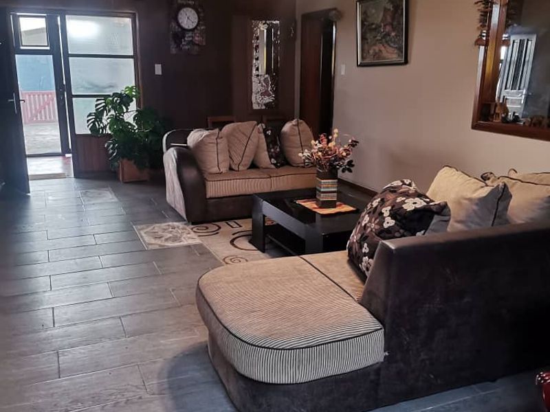 A spacious living room featuring modern grey tiled flooring, a ceiling light fixture, and direct access to an outdoor area through a glass panel door.