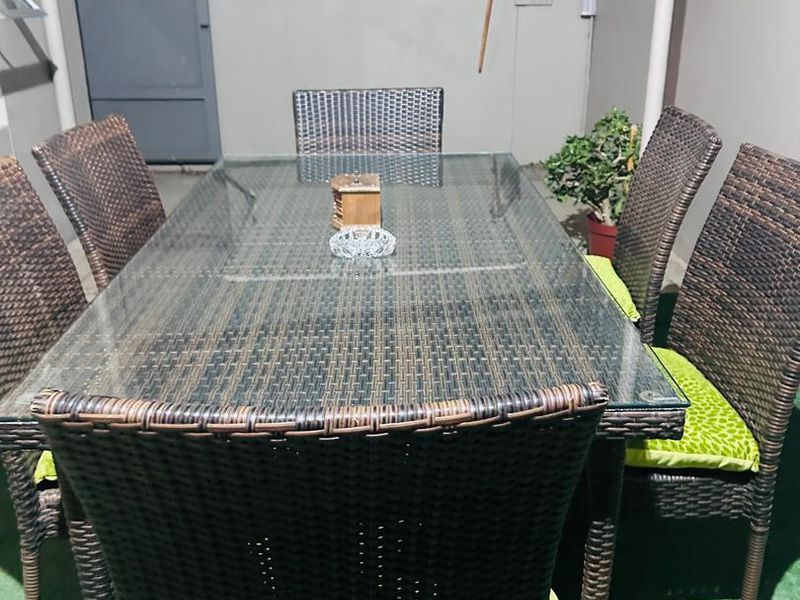 A paved outdoor patio area featuring a wall-mounted drying rack and perimeter security fencing.